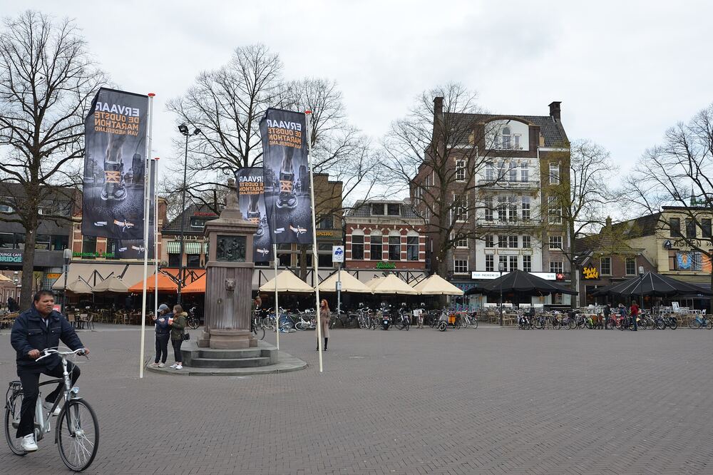 De Grote Markt in Enschede met terrassen, vlaggen en een fietser
